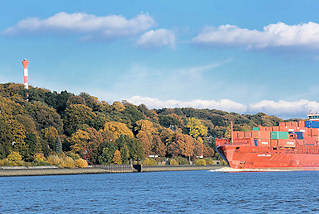 6172 Der Containerfeeder LAURA ANN auf der Elbe vor Hamburg Nienstedten - am Elbhang Herbstbume bis herunter zum Elbufer. Rotes Frachtschiff mit Containerfracht, blauer Himmel weisse Wolken.